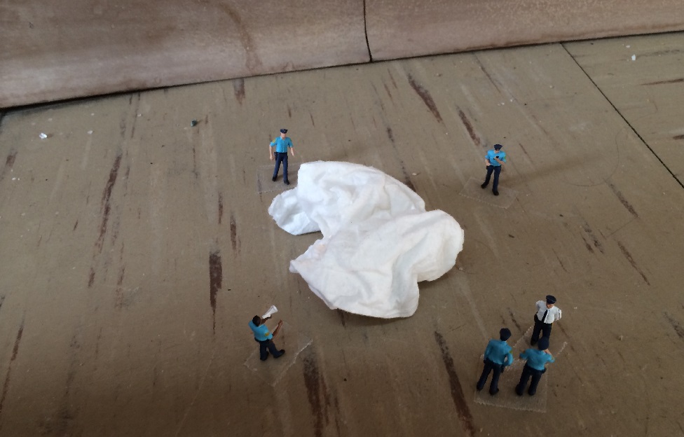 A series of miniature police officer figurines positioned around a fallen tissue.